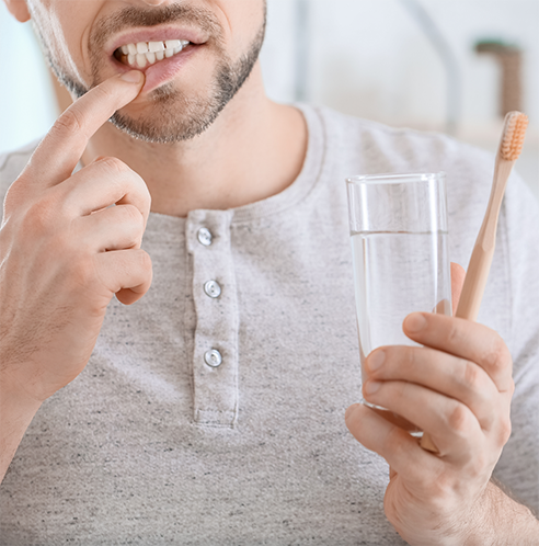 Man holding glass of water and pulling down lip