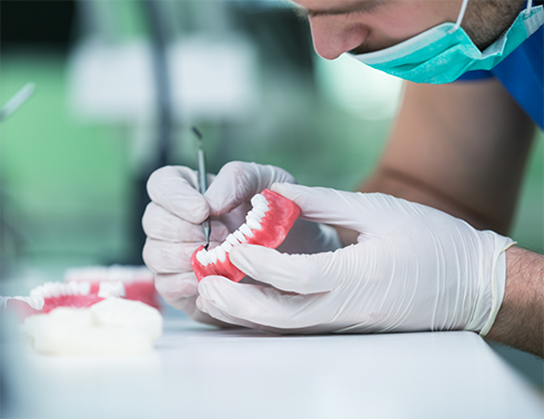 Dental lab technician putting finishing touches on denture