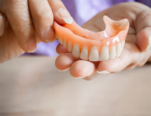Holding a full denture in hand