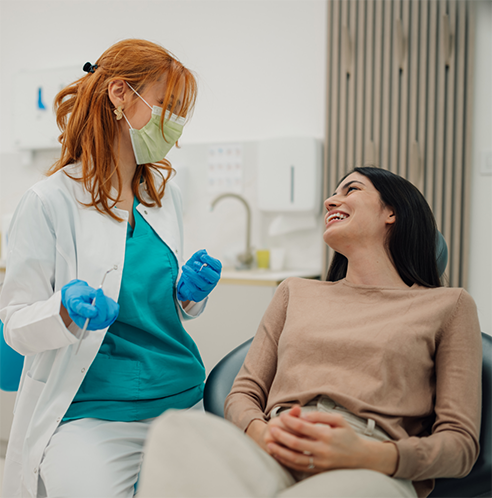 Female dentist with mask talking to smiling patient