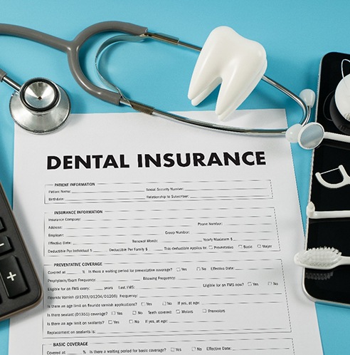 dental insurance form with dental instruments and a calculator
