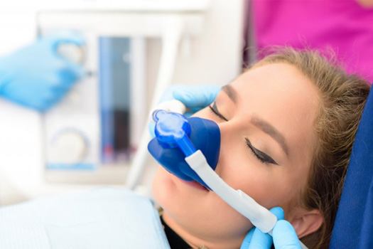 Woman relaxing as dentist administers nitrous oxide via nasal mask