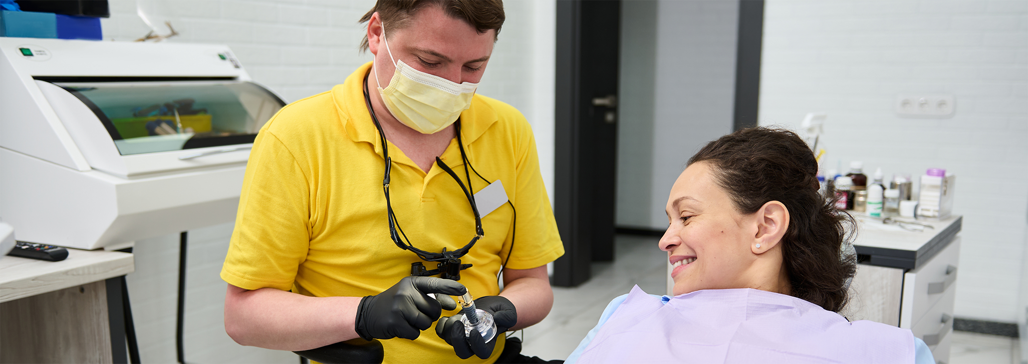 Dentist showing model of dental implant to patient