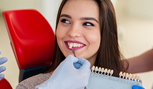 Woman's smile compared with tooth color chart