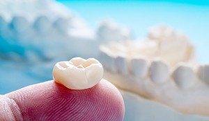 closeup of a finger holding a dental crown