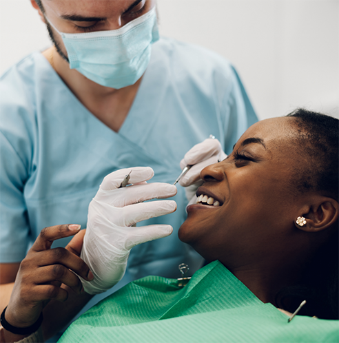 Dentist with mask treating smiling female patient