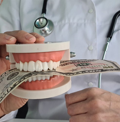 Holding false teeth with money clenched between them