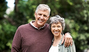 Couple with dental implants in Midland smiling outside