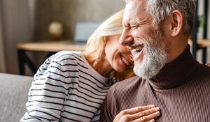 older couple laughing anf sitting on a couch