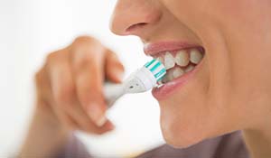 Woman brushing teeth to prevent dental emergencies in Midland