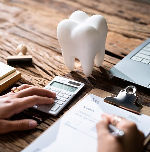 tooth, calculator, computer, and clipboard on a desk