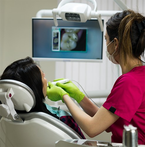 Dentist cleaning patient's smile and looking at teeth on monitor
