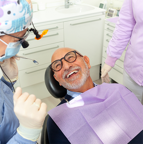 Bearded man with glasses smiling up at dentist