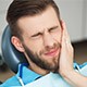 Man in dental chair holding jaw