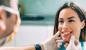 Cosmetic dentist in Midland looking at patient's smile
