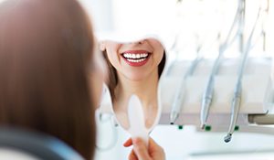 smiling patient looking in a mirror after professional whitening treatment