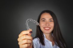 Woman holding up a clear aligner tray 