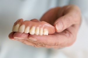 a person holding a top denture in their hands