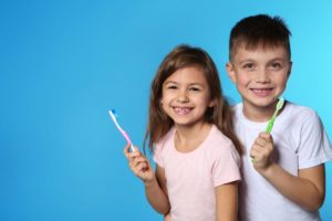 a little girl and boy holding toothbrushes