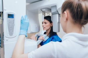 a dental hygienist using a cone beam scanner to capture images of a female patient’s oral cavity