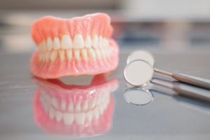 a set of dentures sitting on a desk next to a handheld dental mirror