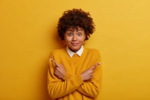 woman pointing and trying to choose a cosmetic dentist