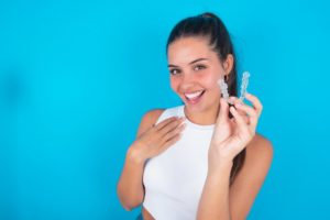 woman smiling and holding Invisalign