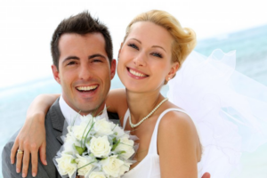 Newlyweds smiling with ocean waves in the background