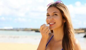 woman applying sun protection on her lips at the beach