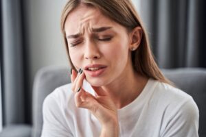 young woman holding her face with a dental emergency