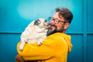 smiling man holding a dog licking his face
