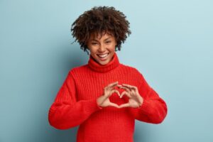 woman smiling and holding her hands in a heart shape