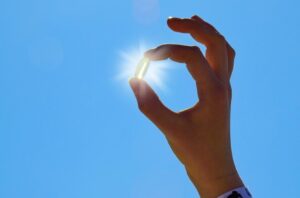 hand holding a Vitamin D supplement up to the sun