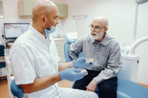 Older man talking to dentist about dental implants